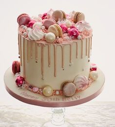 a white cake with pink icing and macaroons on top