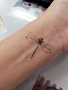 a small dragonfly tattoo on the wrist