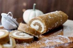 a cinnamon roll is sitting on a cutting board next to pumpkins and other food