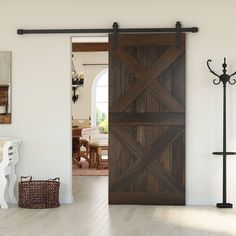 an open barn door in a living room with white walls and wood floors, along with a coat rack