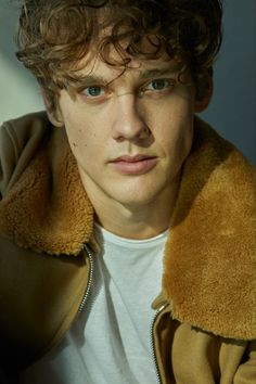 a young man with curly hair wearing a jacket