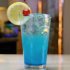 a blue drink with a cherry on the top and lemon wedges in the middle