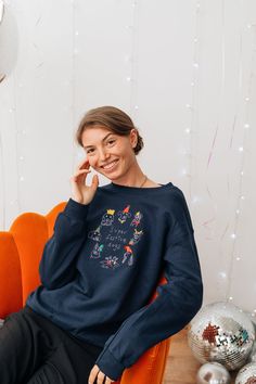 a woman sitting on an orange chair in front of a white wall with balloons and confetti