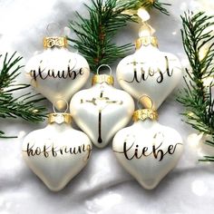 four white christmas ornaments with gold lettering on them