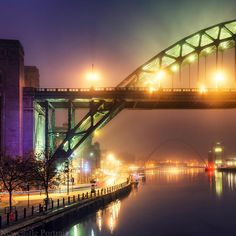 the bridge is lit up at night and reflecting in the water with lights on it