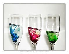 three wine glasses with different colored liquids in them