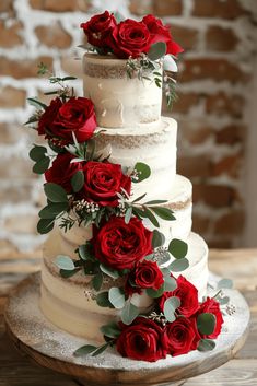 a three tiered wedding cake with red roses on top