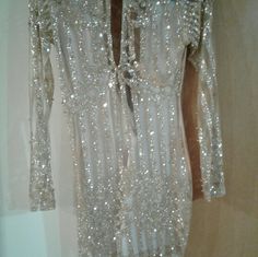 a white dress with sequins on it is hanging in a closet next to a wall