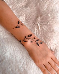 a woman's arm with black leaves on it