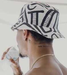 a man with a tattoo on his arm drinking from a water bottle while wearing a hat