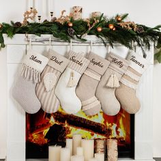 christmas stockings hung over a fireplace with candles