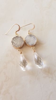 These elegant druzy earrings are handmade with sparkly white round druzy quartz, a sparkly crystal teardrop,  and gold filled ear wires.     A sparkly faceted crystal briollete teardrop is wire wrapped to hang from a round frosty white druzy Quartz, which hangs from a gold filled ear wire.  These beautiful crystal earrings make great earrings for the boho bride or bridesmaid gifts and are available in other colors and also with a mother of pearl drop, shown in last photo and listed separately here: https://www.etsy.com/listing/605777592/druzy-earrings-pearl-drop-earrings  We offer up to 20% discounts for custom bridal party orders.   They are about 2.5 inches long.  Very lightweight.     The second to last photo shows an alternative longer pair with v shape ear wire adding close to an inch Druzy And Shell Earrings, Drop Earrings Gold, Druzy Jewelry, Purple Agate, Druzy Earrings, Agate Earrings, Druzy Quartz, Agate Jewelry, Gold Filled Earrings