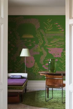 a room with a bed, table and green wallpaper