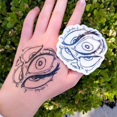 a person's hand with a tattoo on it and an eyeball sticker