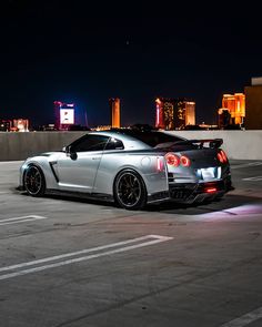 a silver sports car parked on top of a parking lot next to a tall building