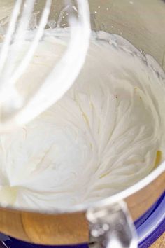 a mixing bowl filled with white batter on top of a wooden table