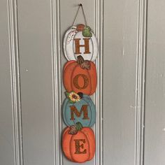 a door hanger decorated with pumpkins and the word home