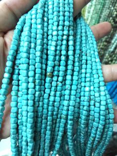 a person is holding some kind of blue beaded corn on the cob in their hand