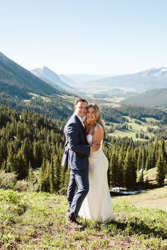 a bride and groom posing for a photo in the mountains