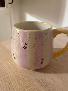 a pink and yellow coffee cup sitting on top of a wooden table