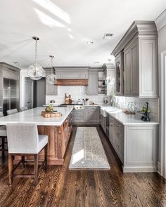 a large kitchen with wooden floors and gray cabinets