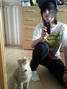 a man taking a selfie with his cat in front of him on the floor