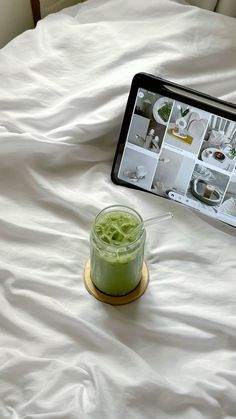 a tablet sitting on top of a bed next to a jar of liquid