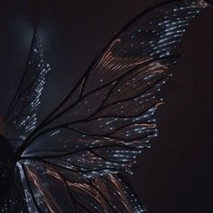 a large butterfly flying through the air with lights on it's wings and body