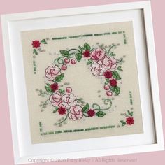 a cross stitch pattern with pink flowers and green leaves in a white frame on a pink background