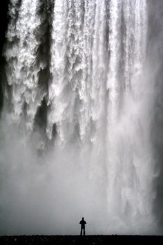 a person standing in front of a large waterfall