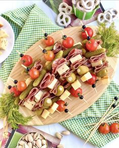 a wooden platter filled with assorted meats and veggies on skewers