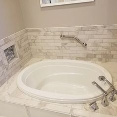 a white bath tub sitting under a window in a bathroom