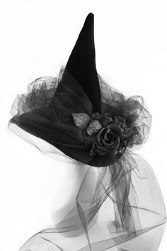 a white mannequin head wearing a black hat with a rose on it's side