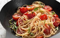 pasta with tomatoes and spinach in a black bowl