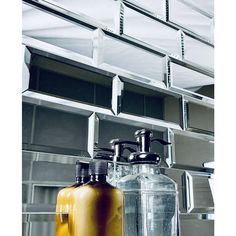 two glass bottles sitting next to each other on a shelf in front of a mirror