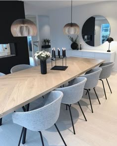 a dining room table with chairs and candles on it in front of a large mirror