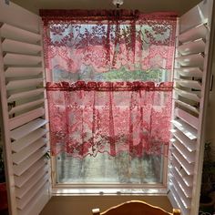 the window is covered with pink lace curtains