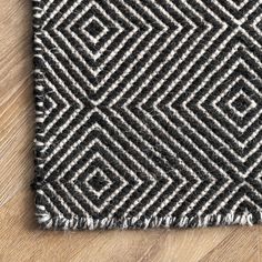 a black and white rug with fringes on top of wood flooring, viewed from above