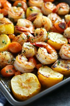 Roasted shrimp, lemon slices, and vegetables on a baking sheet.