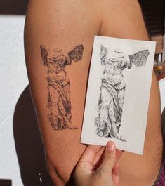 a person holding up a piece of paper with an angel and demon tattoo on it