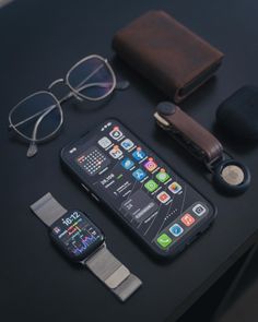 an apple watch, wallet, and other items are on a black table with glasses