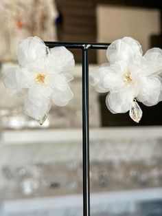 two white flowers on a metal stand with water drops hanging from it's petals