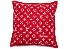 a red and white pillow with the word supreme on it