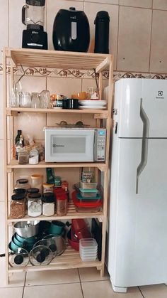 a white refrigerator freezer sitting next to a wooden shelf