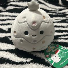 a white hello kitty ball sitting on top of a black and white striped blanket next to a green tag