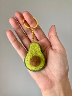 a hand holding an avocado keychain in it's left hand