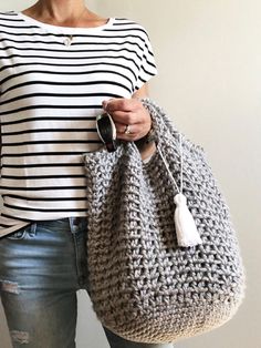 a woman holding a gray crocheted purse