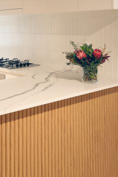 a vase with flowers sitting on top of a kitchen counter