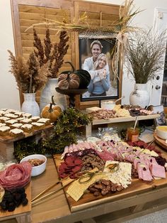 a wooden table topped with lots of food and desserts next to a framed photo