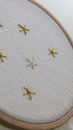 a close up of a cross stitch with gold stars on it